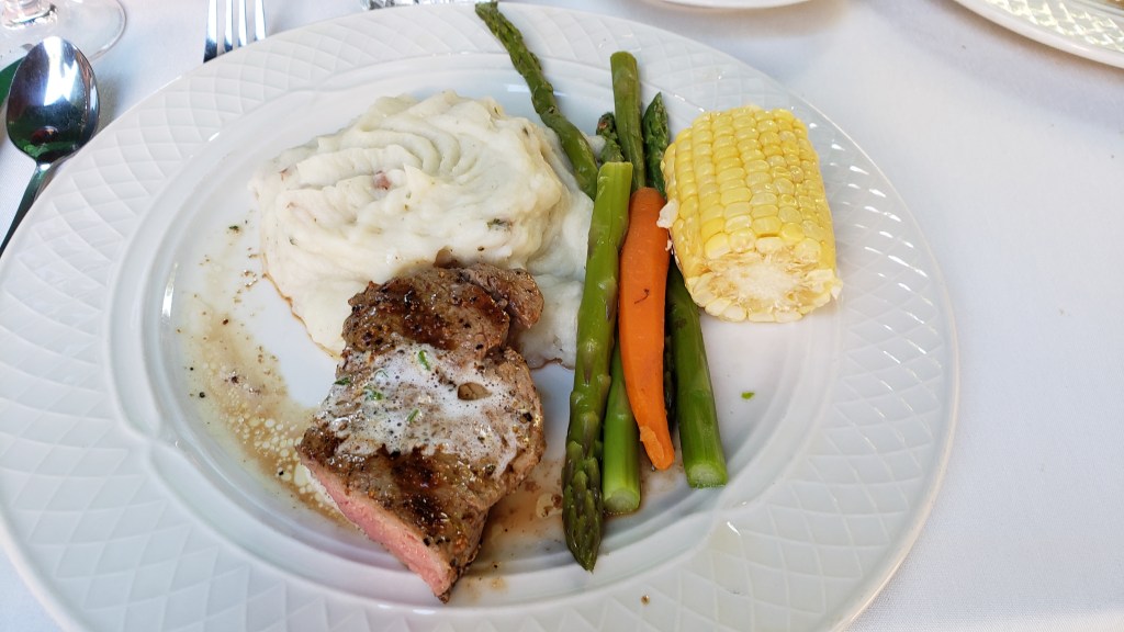 Steak smothered in butter with asparagus, corn and carrots and a pile of garlic mashed potatoes.