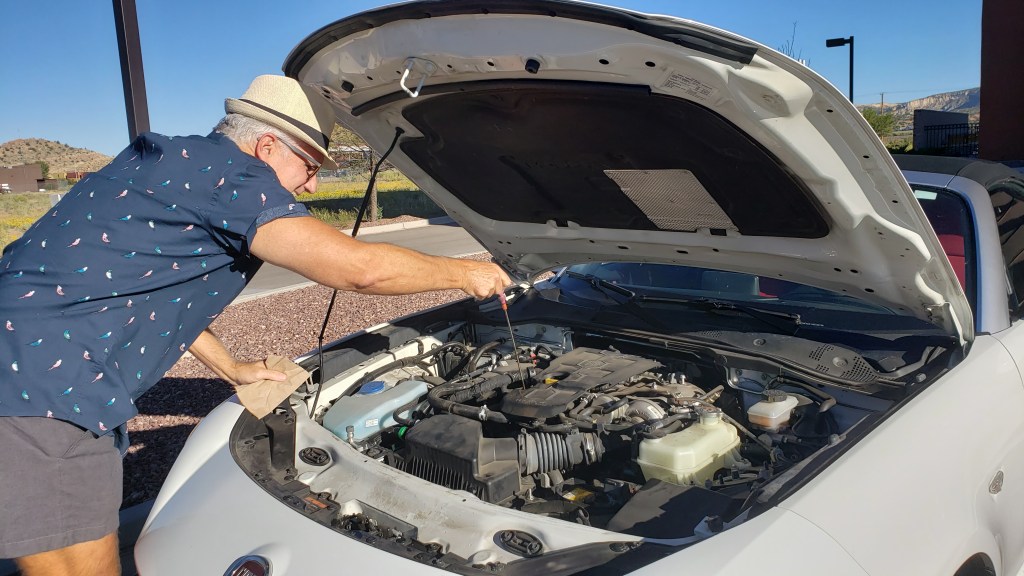 Man checking oil in car engine.
