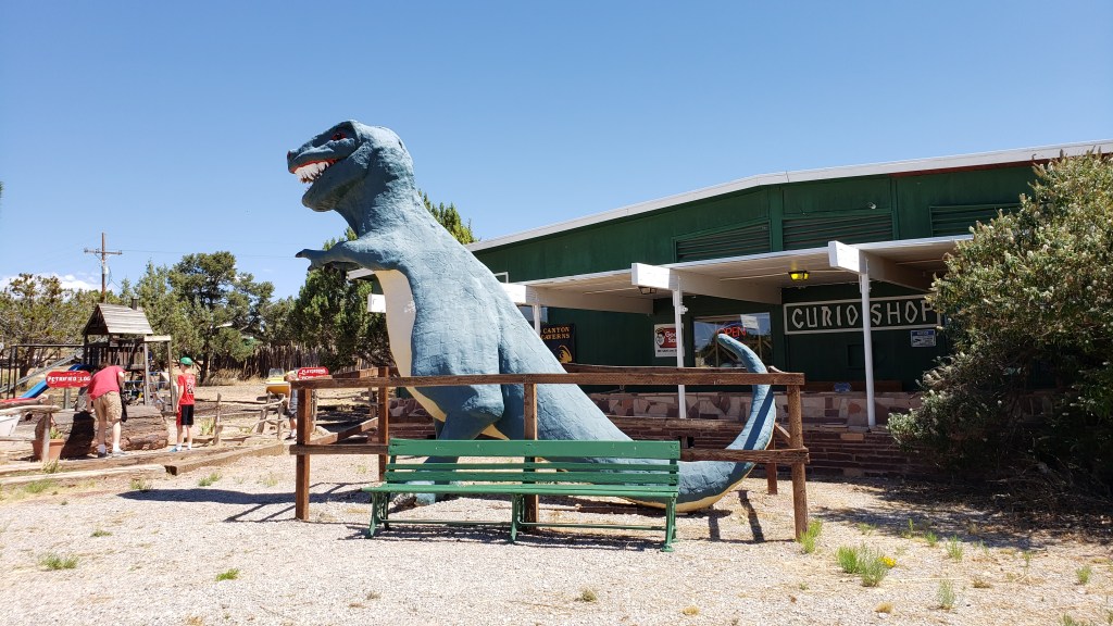 dinosaur statue in front of entrance to caves