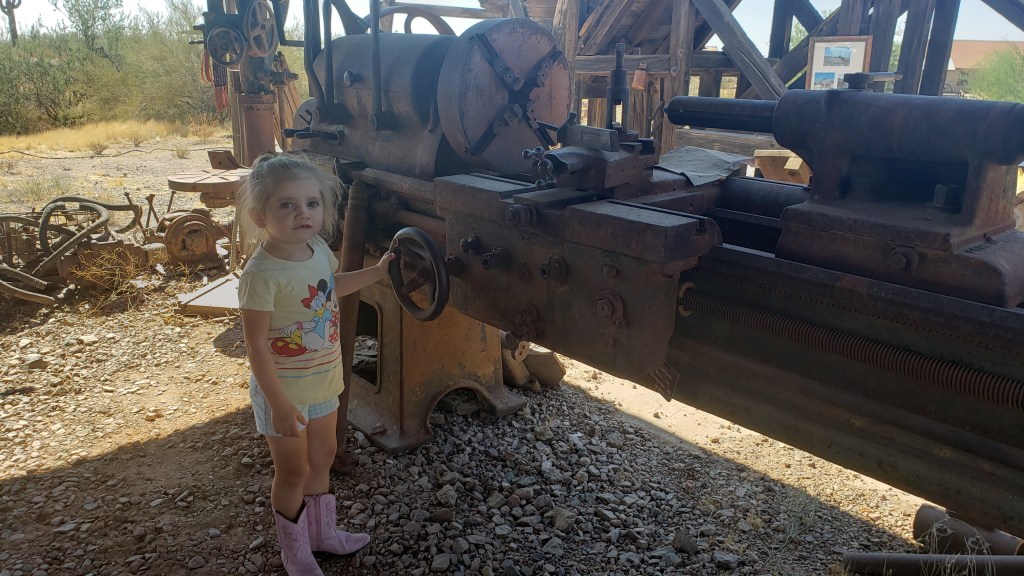child standing next to abandoned mine equipment